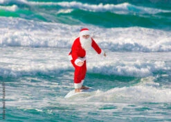 Fotografia Christmas Santa Claus Windsurfer Surfing With Surfboard At Ocean Waves