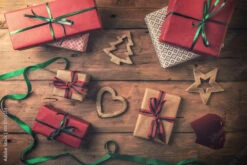 Fotografia Christmas Gifts And Decorations On Brown Wooden Background