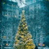 Fotografia Snow-covered Christmas Tree With Golden Lights Glowing Against A Stark Urban Bac