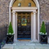 Fotografia Georgian Front Door, Decorated For Christmas With Festive Green Holiday Wreath And Two Trees In Plant Pots