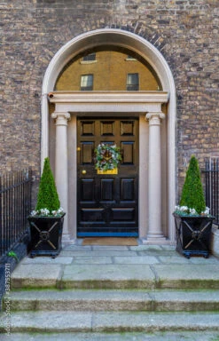 Fotografia Georgian Front Door, Decorated For Christmas With Festive Green Holiday Wreath And Two Trees In Plant Pots